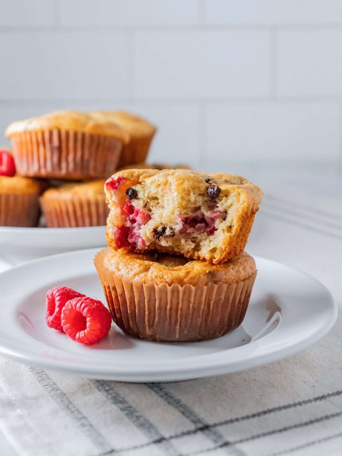 Stacked raspberry muffins with a bite taken out of the top one.