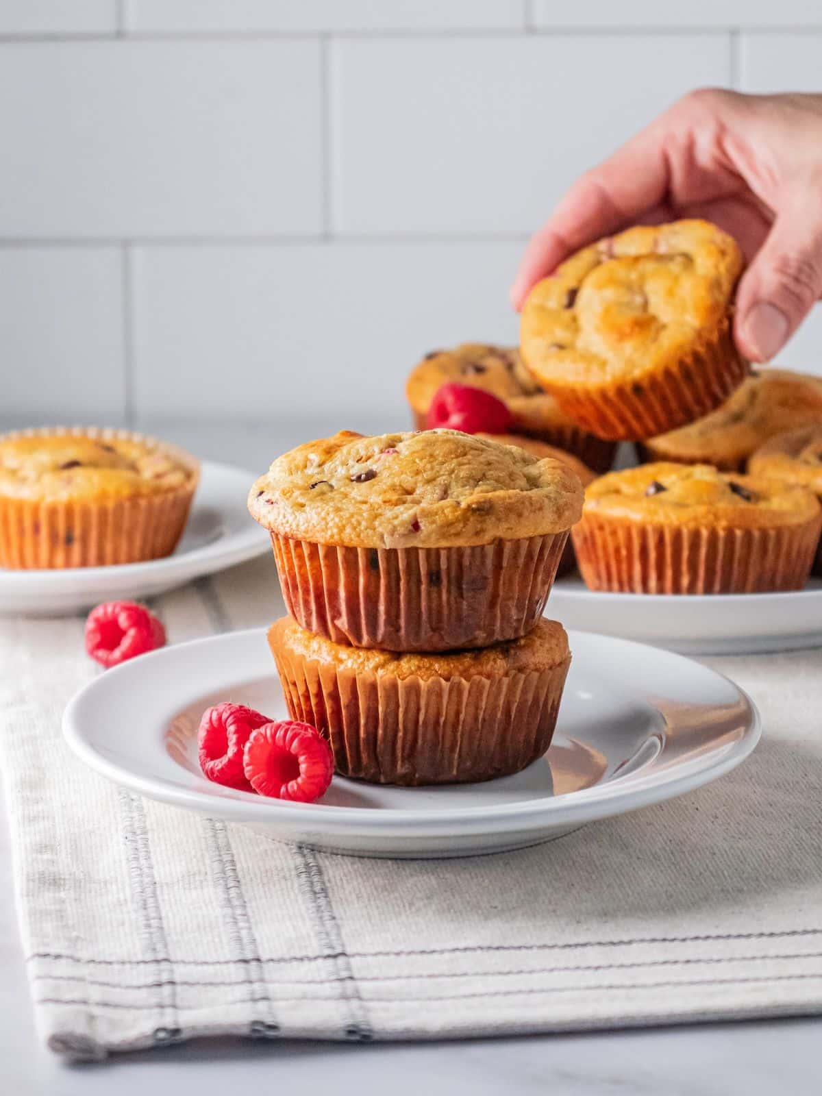 A stack of raspberry muffins with the top being removed from the back plate.