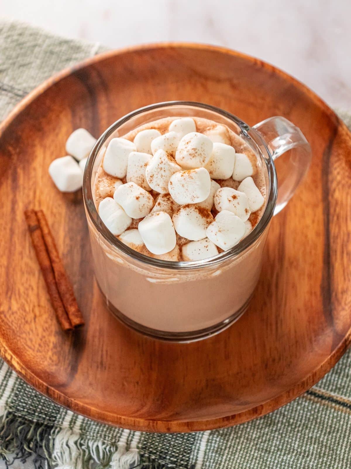 A mug full of peanut butter hot chocolate on a wooden plate.