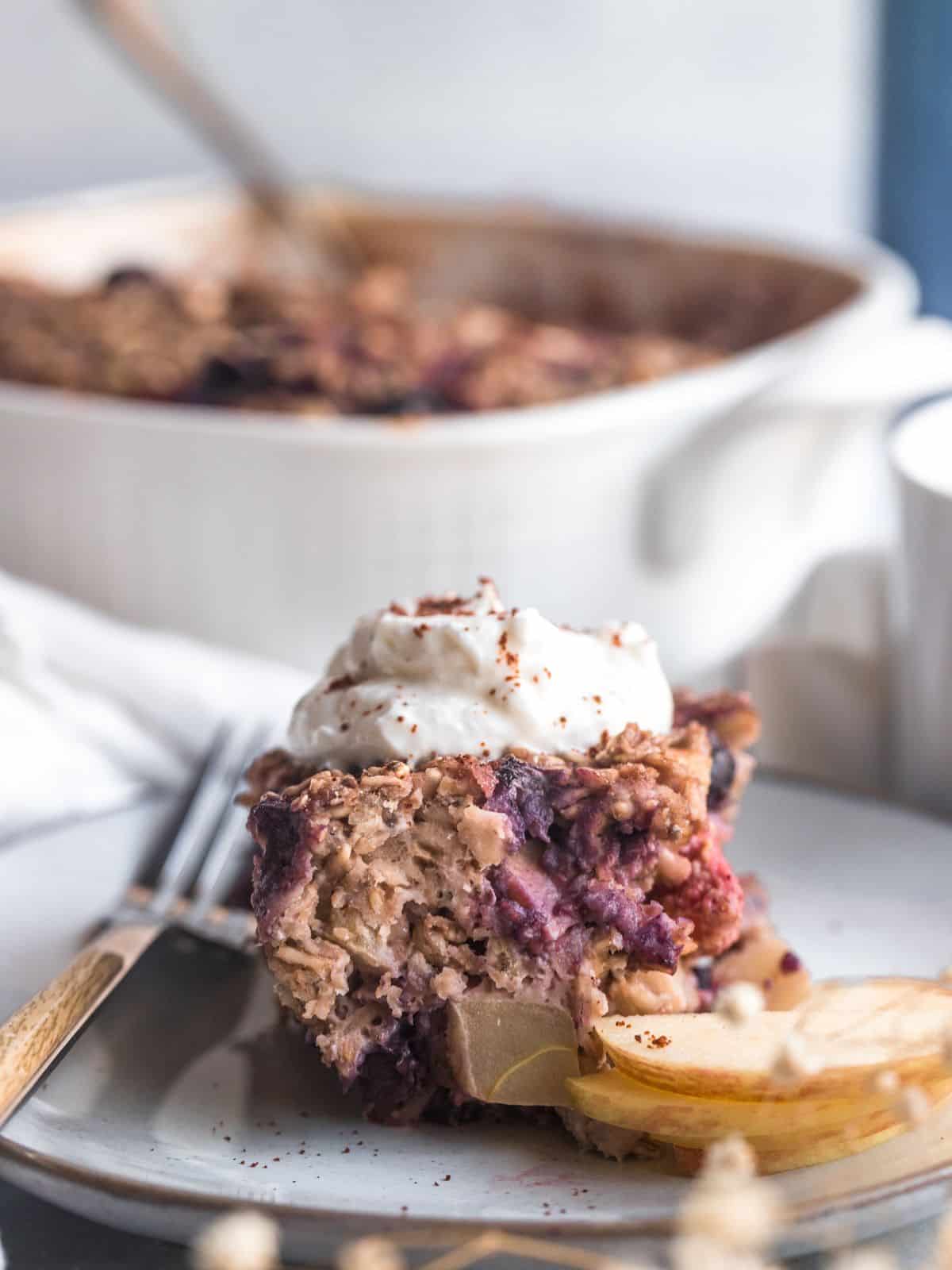 A portion of protein baked oats on a plate with some sliced pears and topped with Greek yogurt.