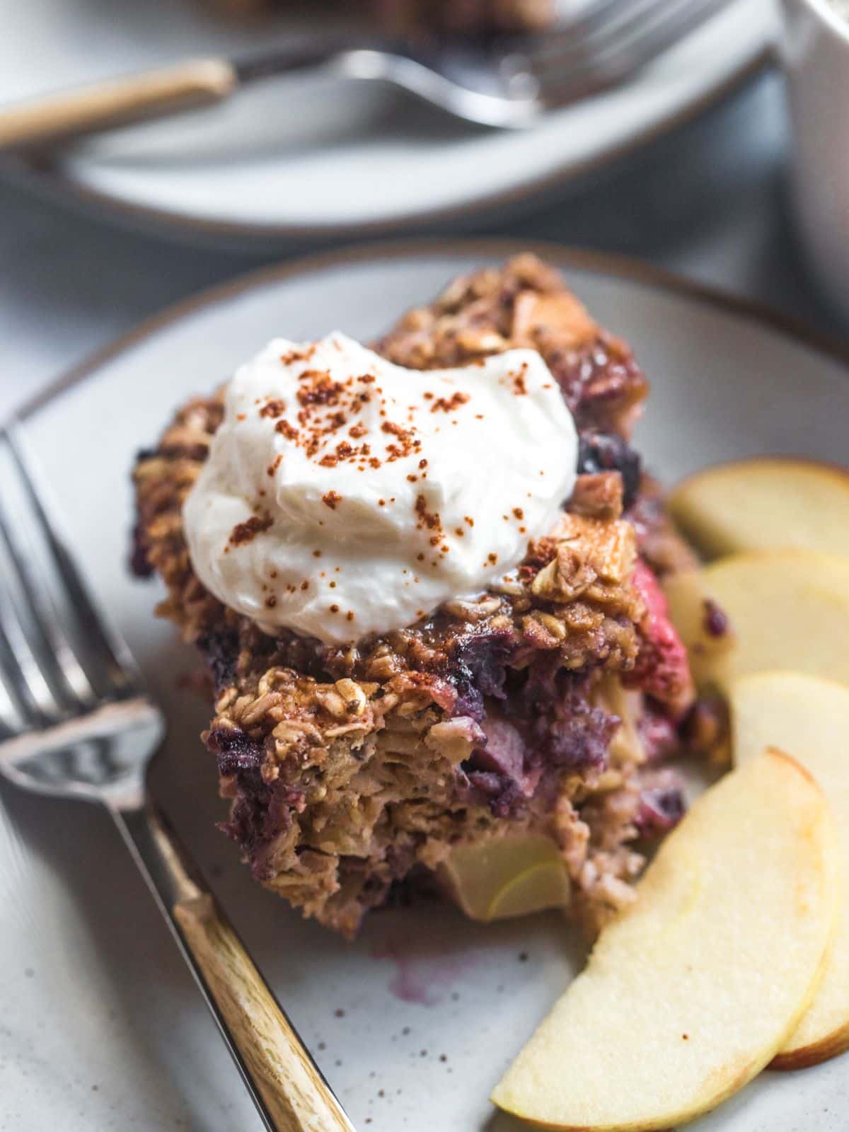 A slice of baked protein oats on a plate topped with some Greek yogurt and a fork to the side.