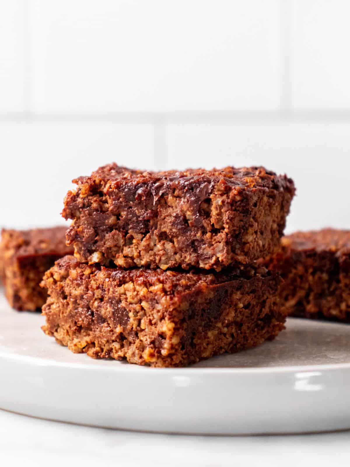 Two quinoa brownies stacked ona. white plate.