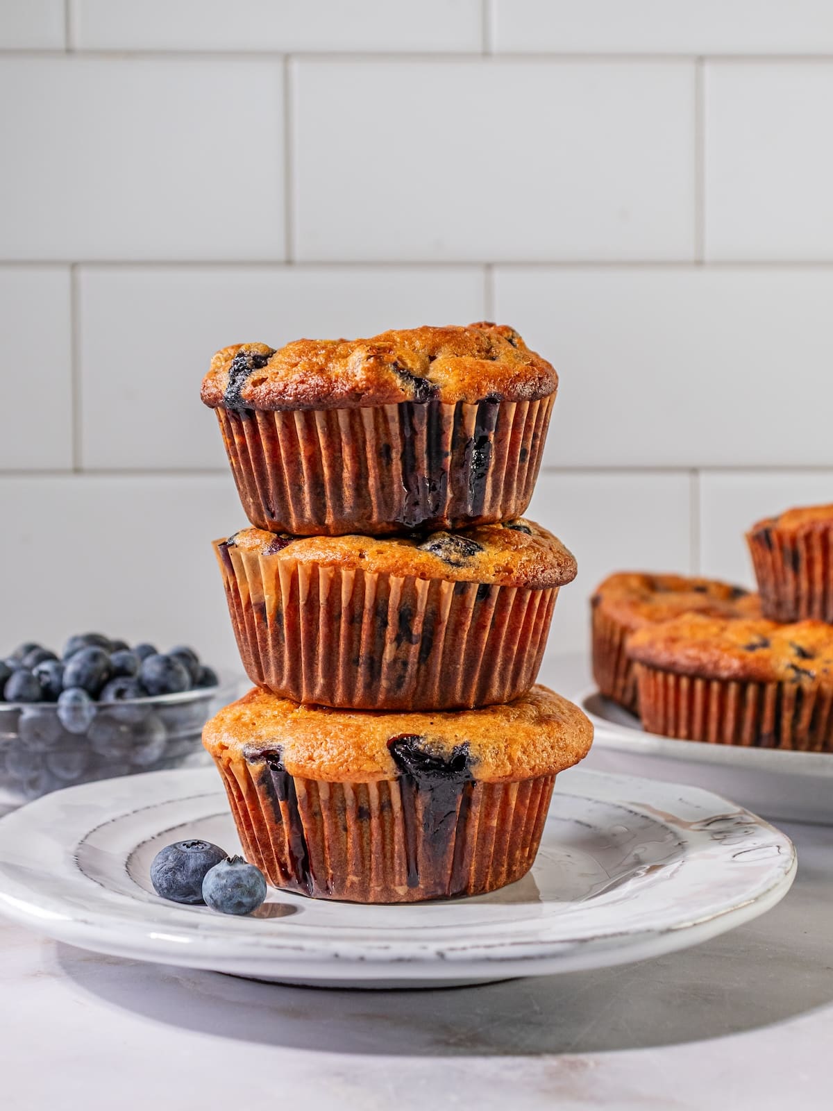 stack of blueberry muffins on a white plate.
