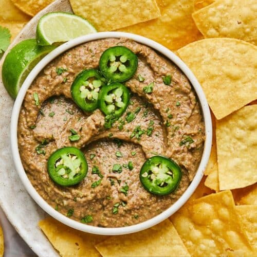 A bowl of spicy black bean hummus without tahini surrounded by chips.