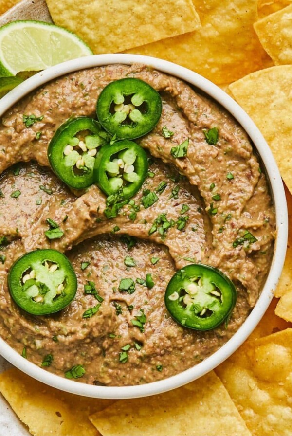 A bowl of spicy black bean hummus without tahini surrounded by chips.