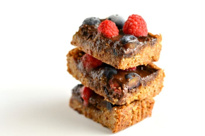 Grain free, vegan Chocolate Berry Bars made with an almond, coconut crust, generously filled with a luscious chocolate sauce and topped with a garden of fresh berries. This decadent treat is a healthy dessert that will satisfy any sweet tooth!