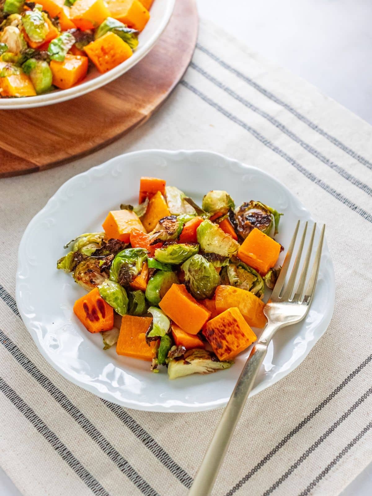 Brussels sprouts salad on a plate with a fork and a bowl of more salad in the background.