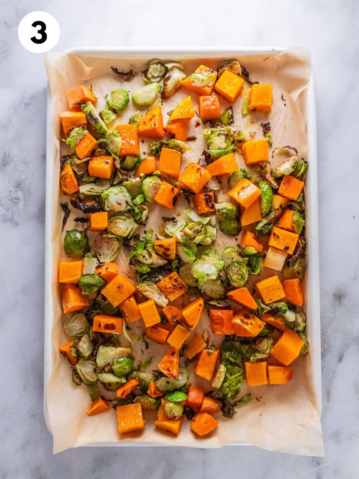 Vegetables on the baking sheet with the dressing added.