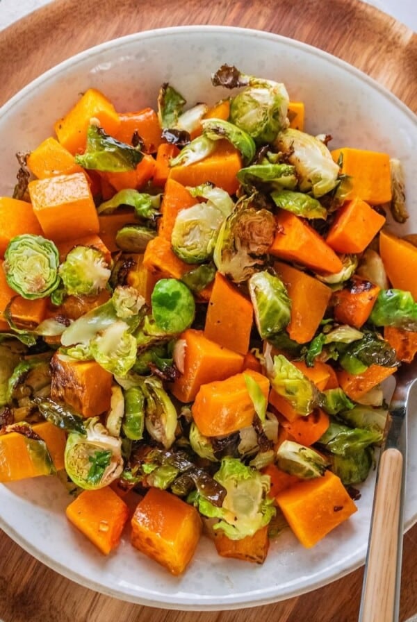 A plate of roasted Brussels sprouts salad with a spoon resting to the side.