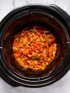 slow cooker with shredded chicken and sliced bell peppers