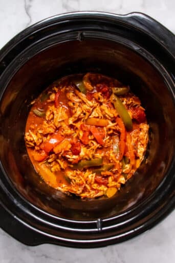 slow cooker with shredded chicken and sliced bell peppers