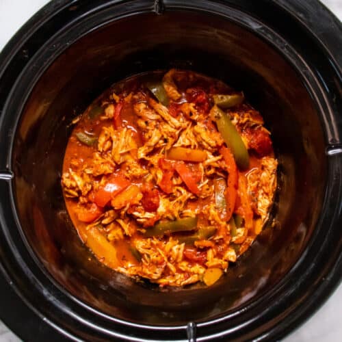 slow cooker with shredded chicken and sliced bell peppers