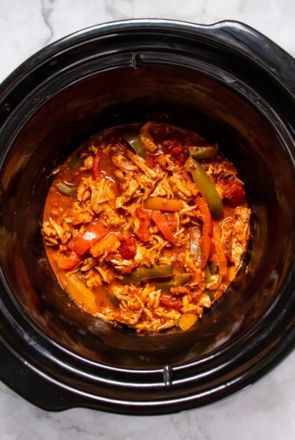 slow cooker with shredded chicken and sliced bell peppers