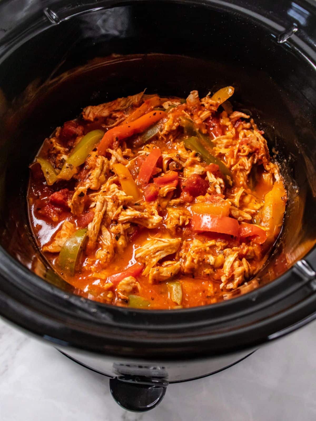 Cooked crockpot chicken and peppers in the crockpot.