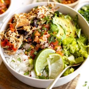 Slow cooker chicken taco bowls served up in a white bowl on the table.