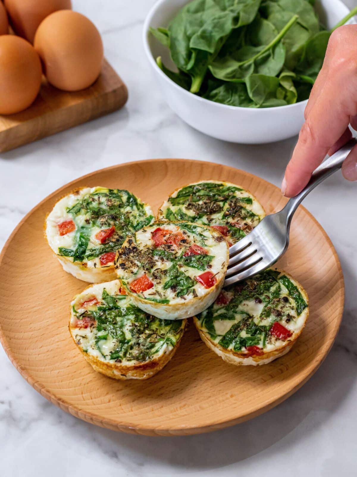 A fork lifting a Starbucks copycat egg white bite from a plate with them stacked on top of each other.
