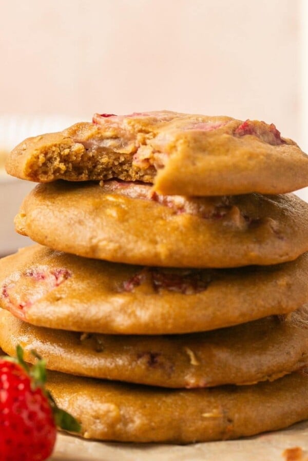 A stack of strawberry oatmeal cookies with the one on top missing a bite.