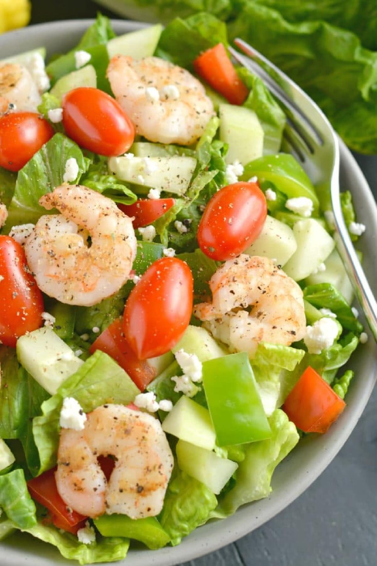 salad with shrimp, feta and grape tomatoes in a gray bowl.