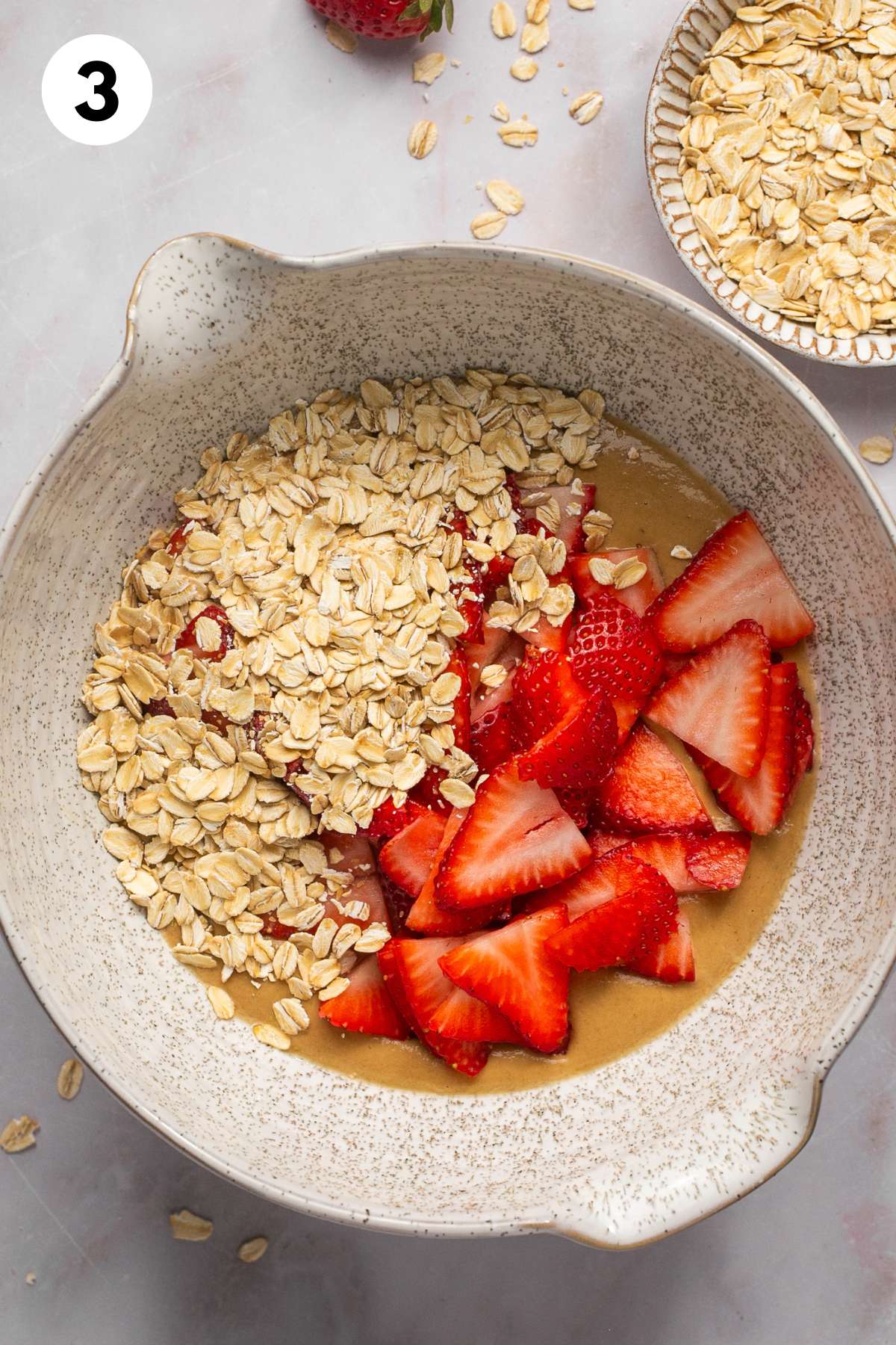 Oats and strawberries are added to the bowl of cookie batter.