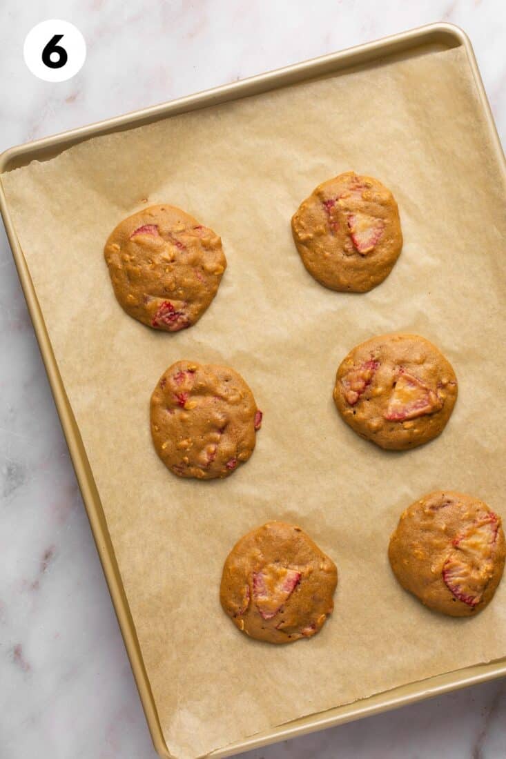 Strawberry oatmeal cookies on a baking tray after cooking.