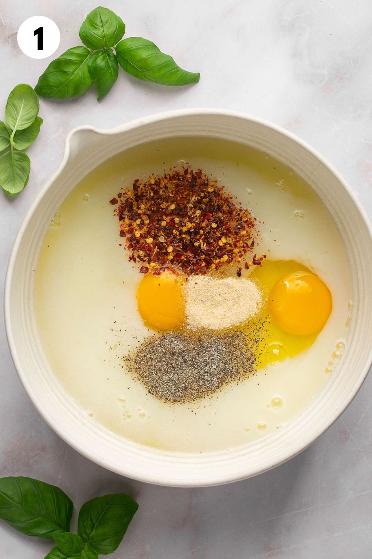 Eggs, milk, and seasonings added to a mixing bowl.