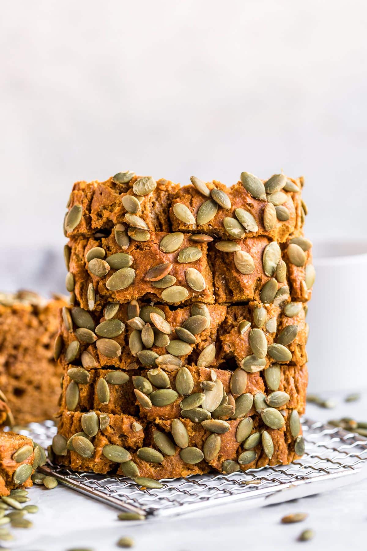 Slices of paleo pumpkin bread stacked on top of each other on a wire rack.