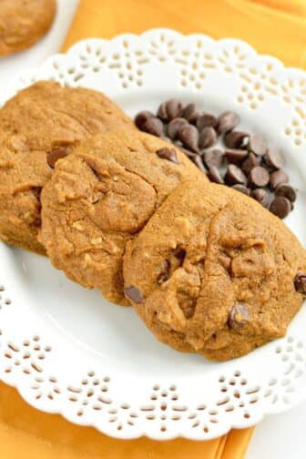 A stack of gluten free pumpkin chocolate chip cookies with a bite missing from the one on top.