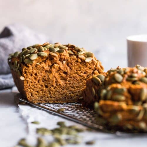 Gluten free sugar free pumpkin bread on a wire rack with a few slices cut and leaning over in front.