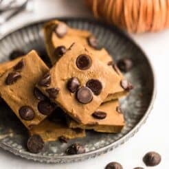 Pumpkin protein bars with chickpeas and chocolate chips on a gray plate with chocolate chips on the counter.
