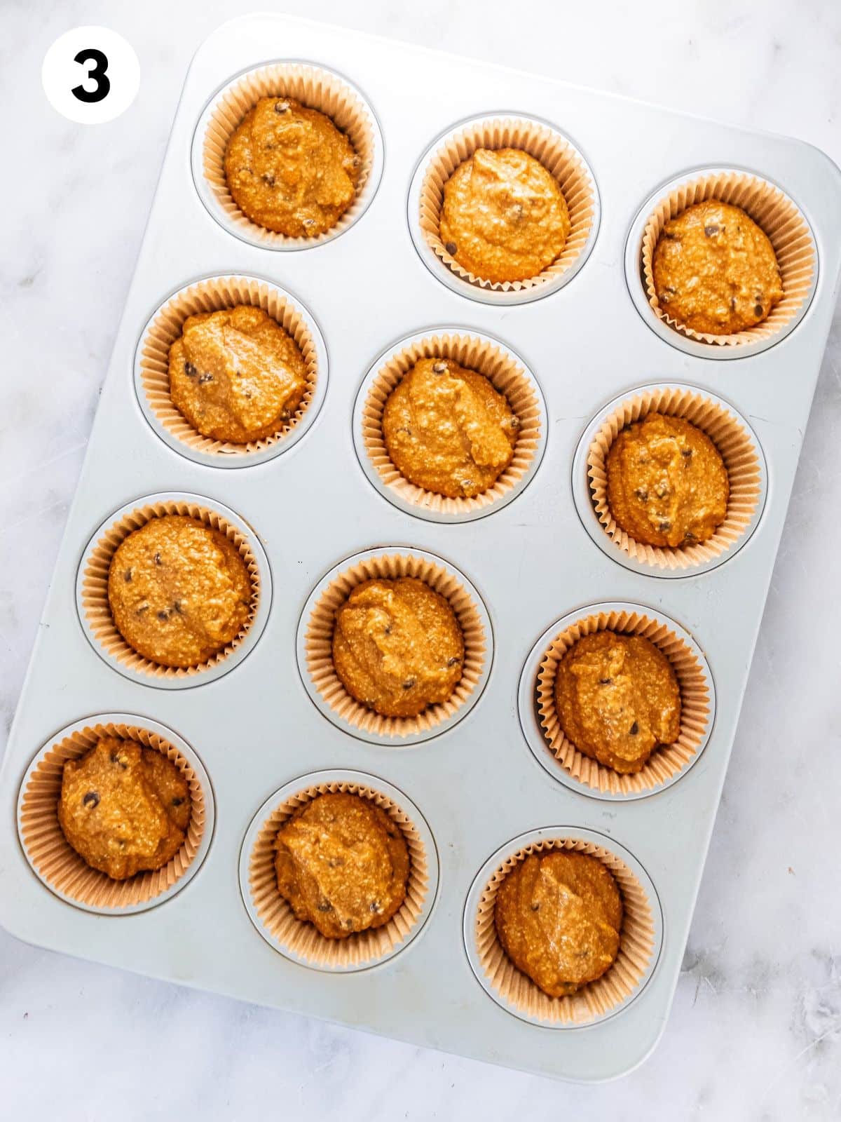 Pumpkin oatmeal muffin batter in a muffin tin.