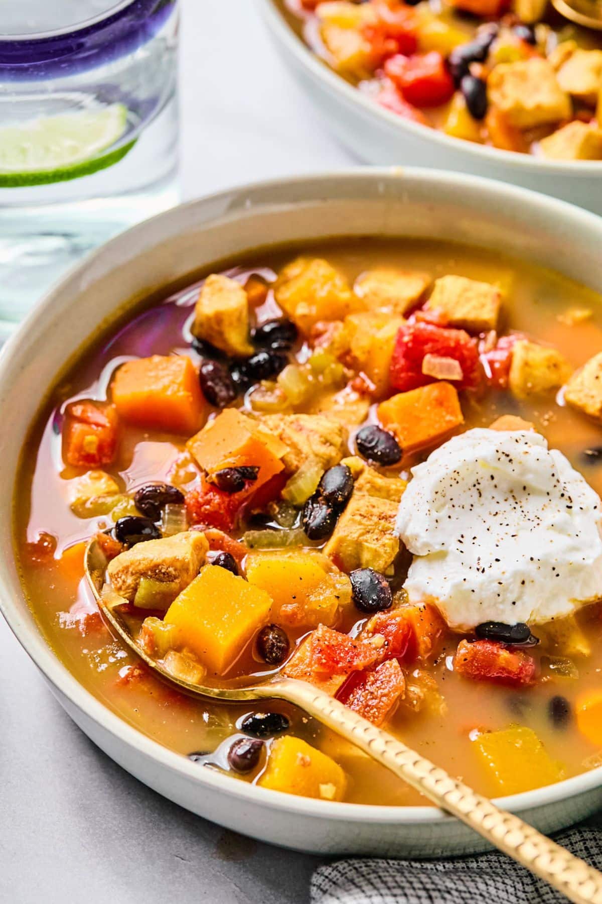 A bowl of red chicken chili with a spoon resting in the bowl.