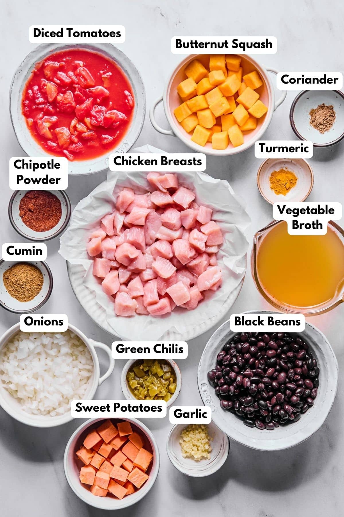 Ingredients to make a tomato-based chicken chili in bowls.