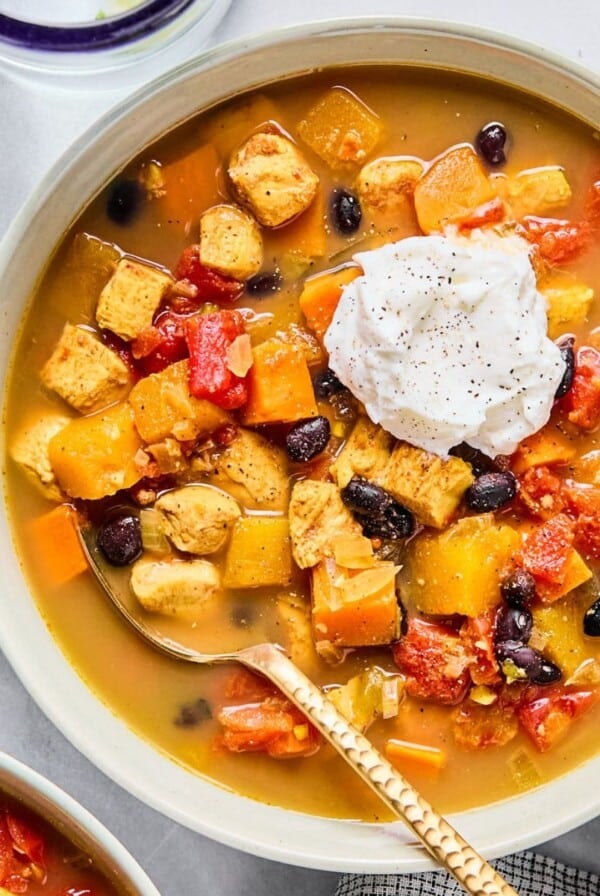 Red chicken chili with sweet potatoes and butternut squash in a bowl.