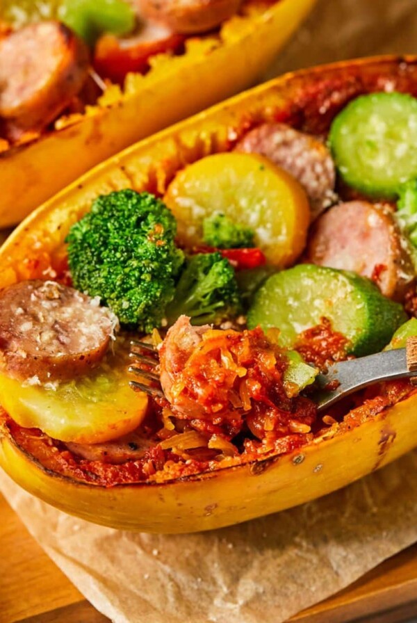 Spaghetti squash pizza boats on a piece of parchment with a fork resting in it.