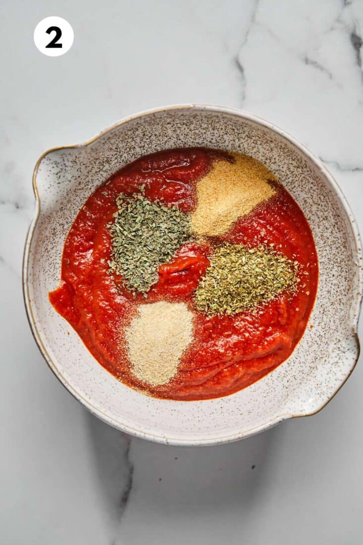 Tomato sauce in a bowl with seasonings added.