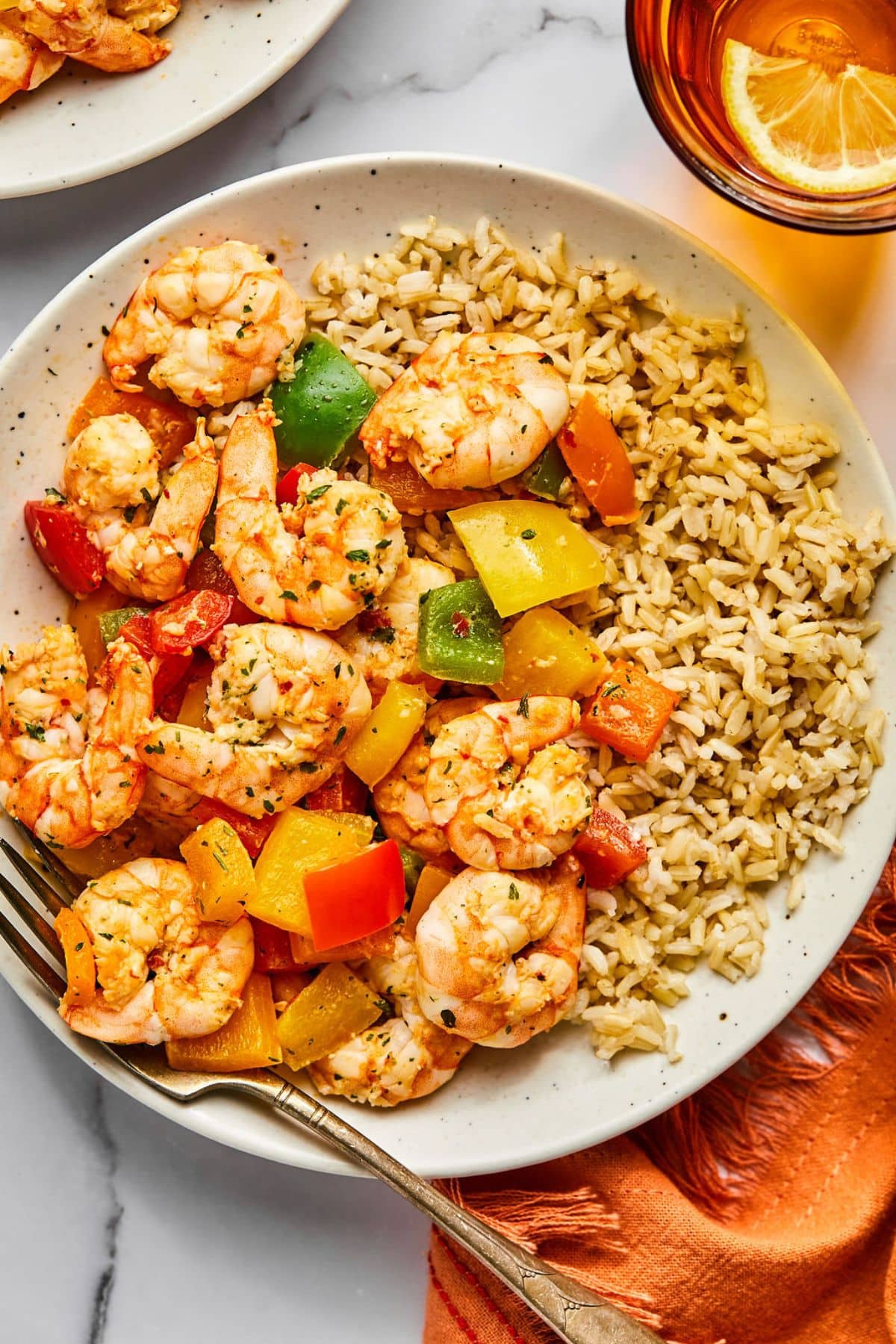 Shrimp with vegetables and rice on a plate with a fork resting to the side.