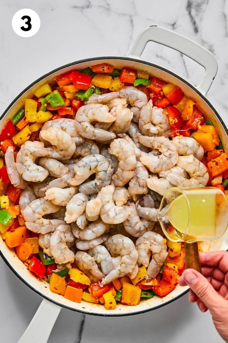 Raw shrimp added to the skillet with the vegetables.
