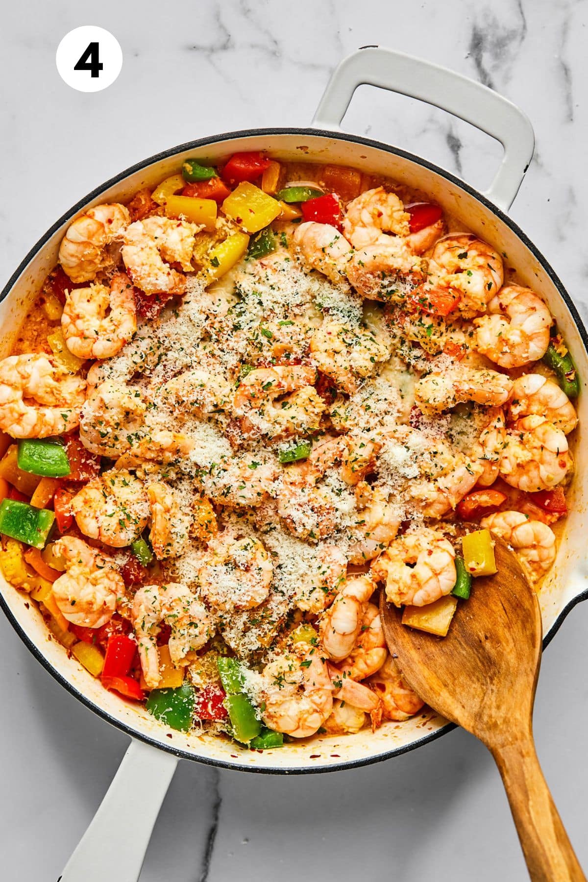 Seasonings added to the skillet with a wooden spoon resting on the side.