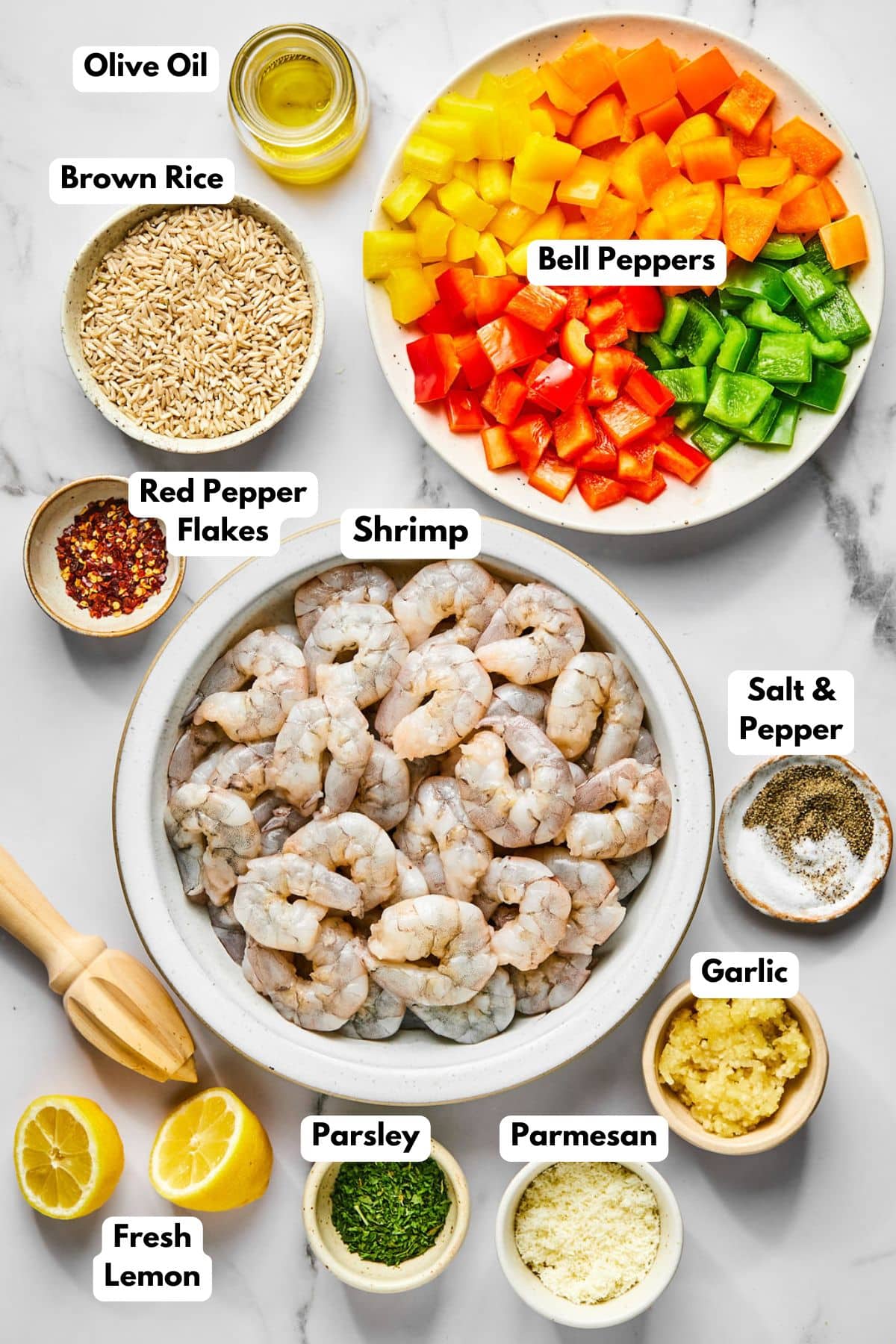 Ingredients to make shrimp and rice in bowls on a table with labels for each to the side.