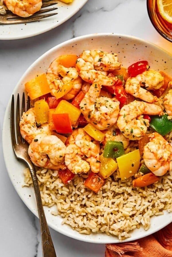 A colorful shrimp and rice recipe on a white plate with bell peppers.