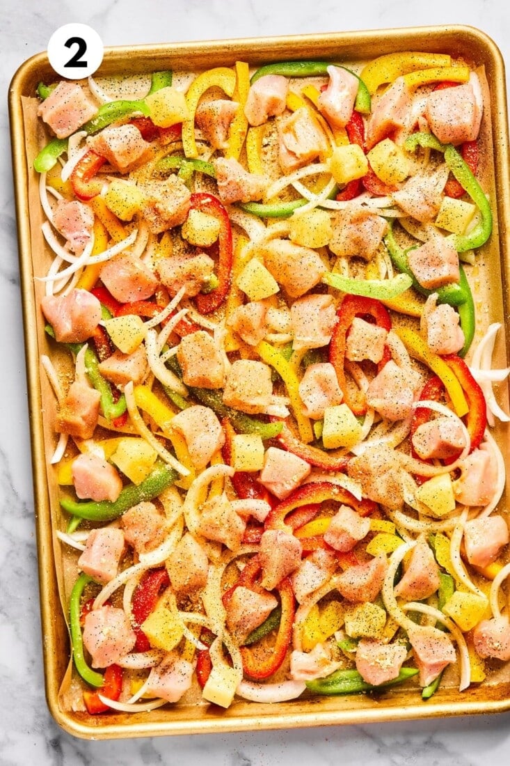 Chicken added to the baking pan with the vegetables. 