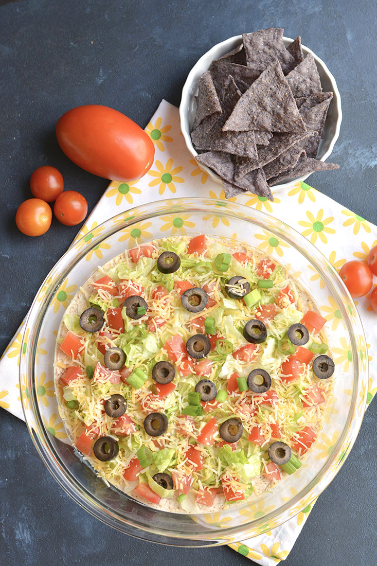Healthy Taco Dip made with tangy, protein packed Greek Yogurt & homemade taco seasoning! Your guests will have no idea this flavorful party dip is healthy! Gluten Free + Low Calorie 