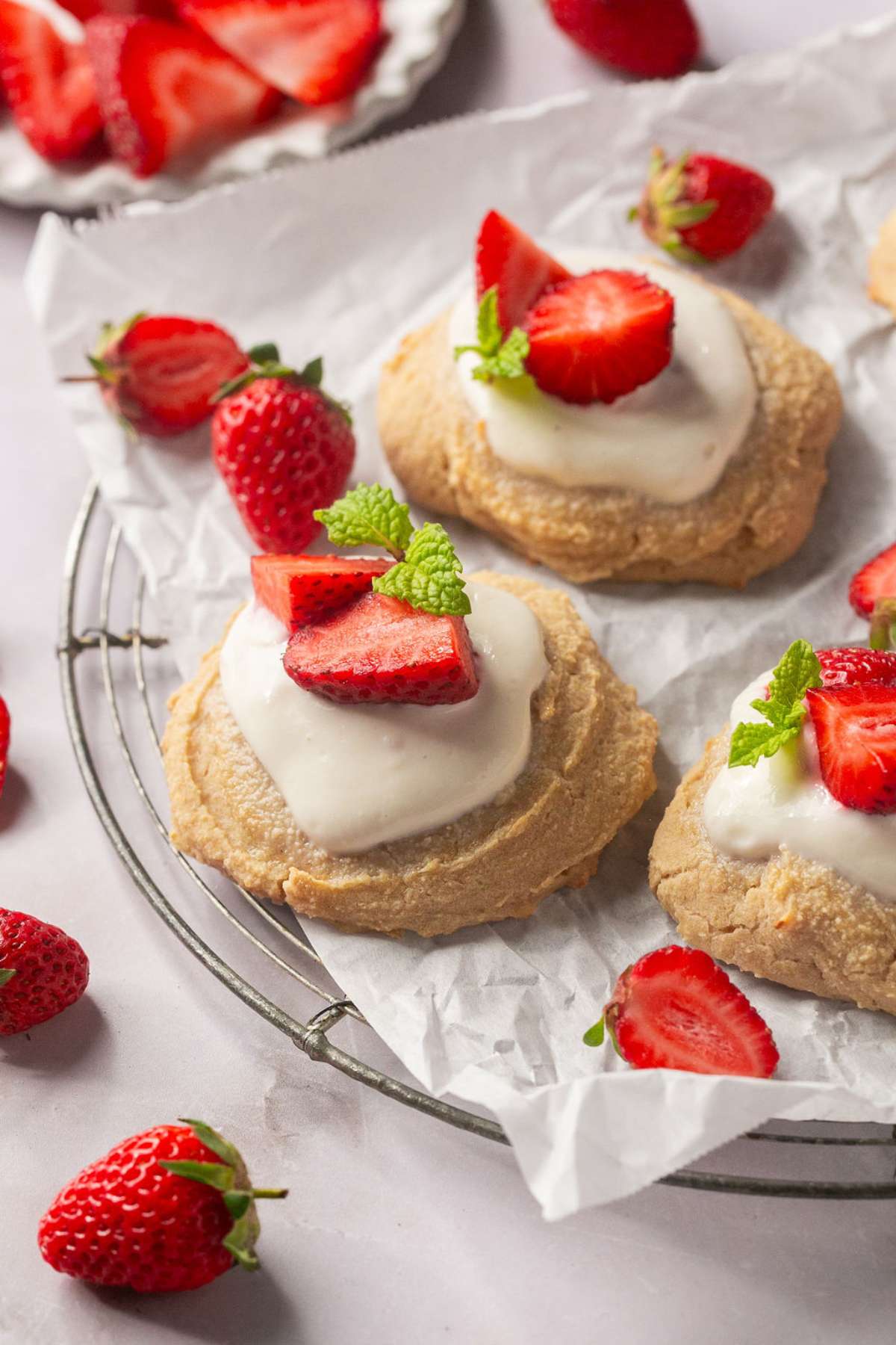 Healthy strawberry shortcake on a wire rack topped with a piece of parchment and garnished with fresh berries.