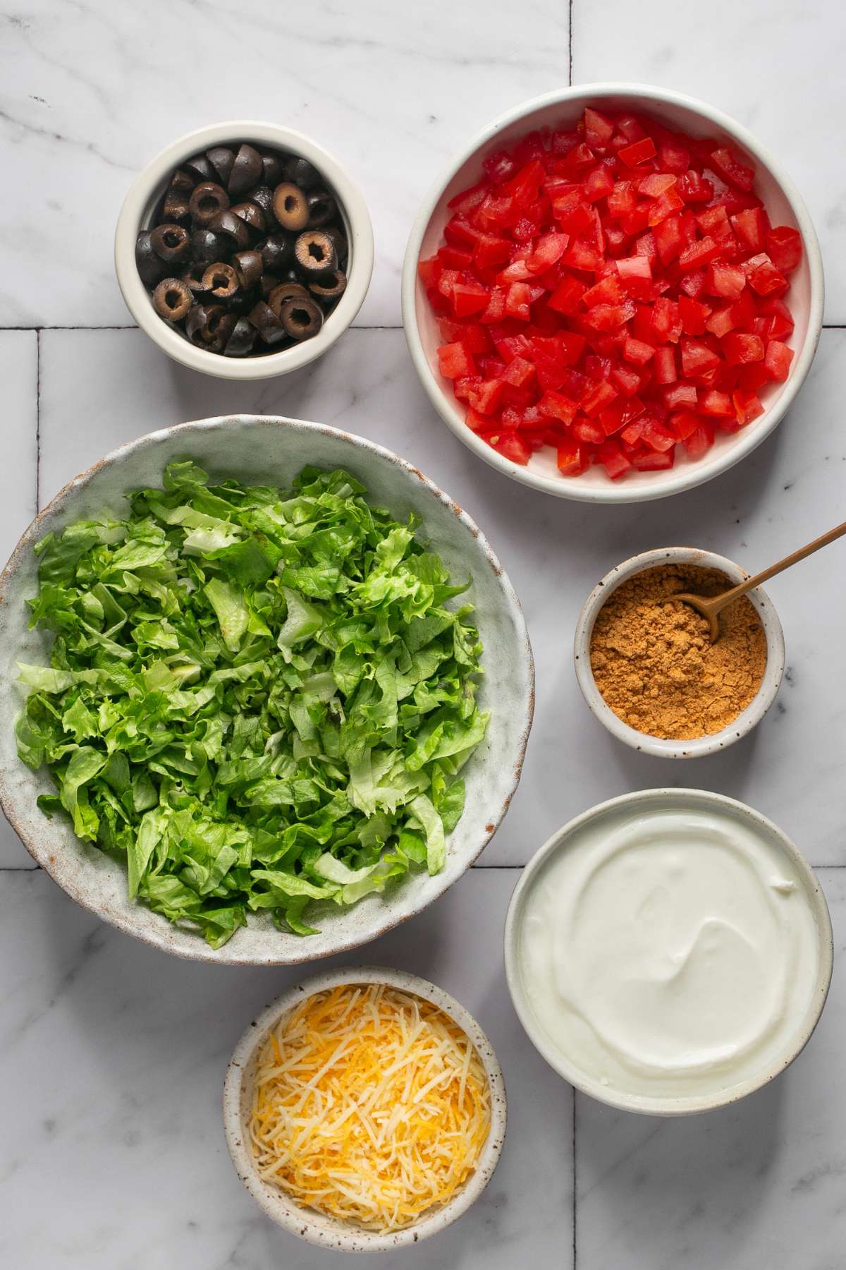 Ingredients to make taco dip on the table before mixing.
