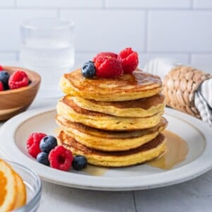 Almond flour pancakes stacked on a plate with berries on top.