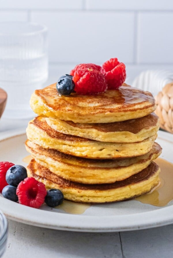 Almond flour pancakes stacked on a plate with berries on top.