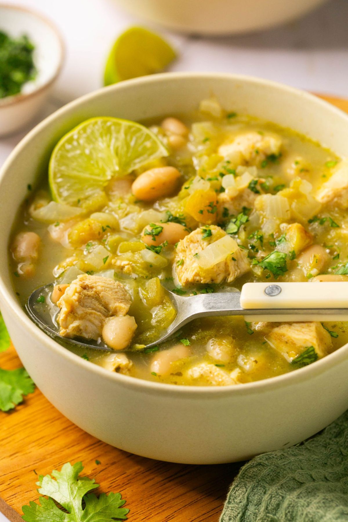 A bowl of healthy white chicken chili on the table with a spoon in the bowl. 