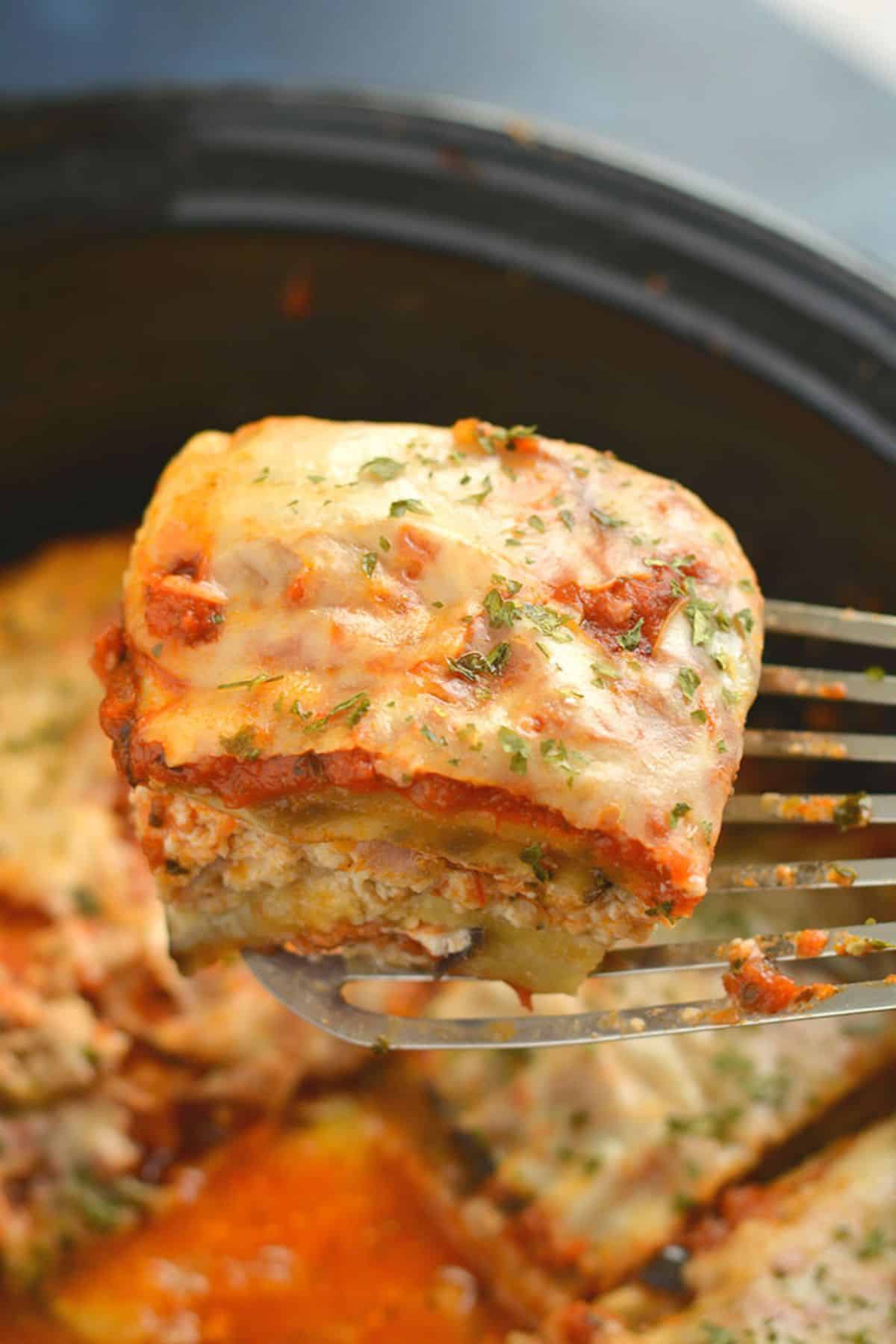 A slice of low carb lasagna being lifted out of a crockpot with a spatula.