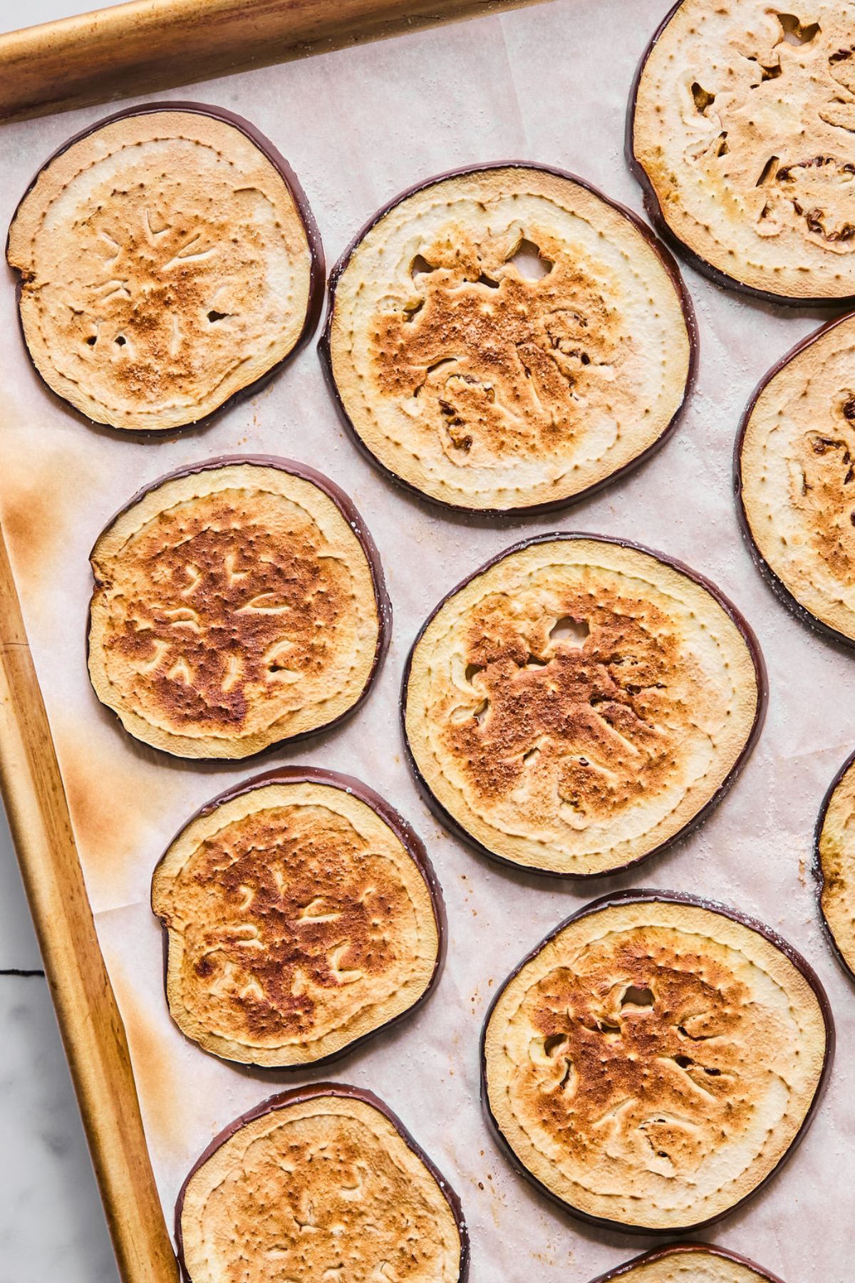 Seasoned eggplant slices on a baking sheet.