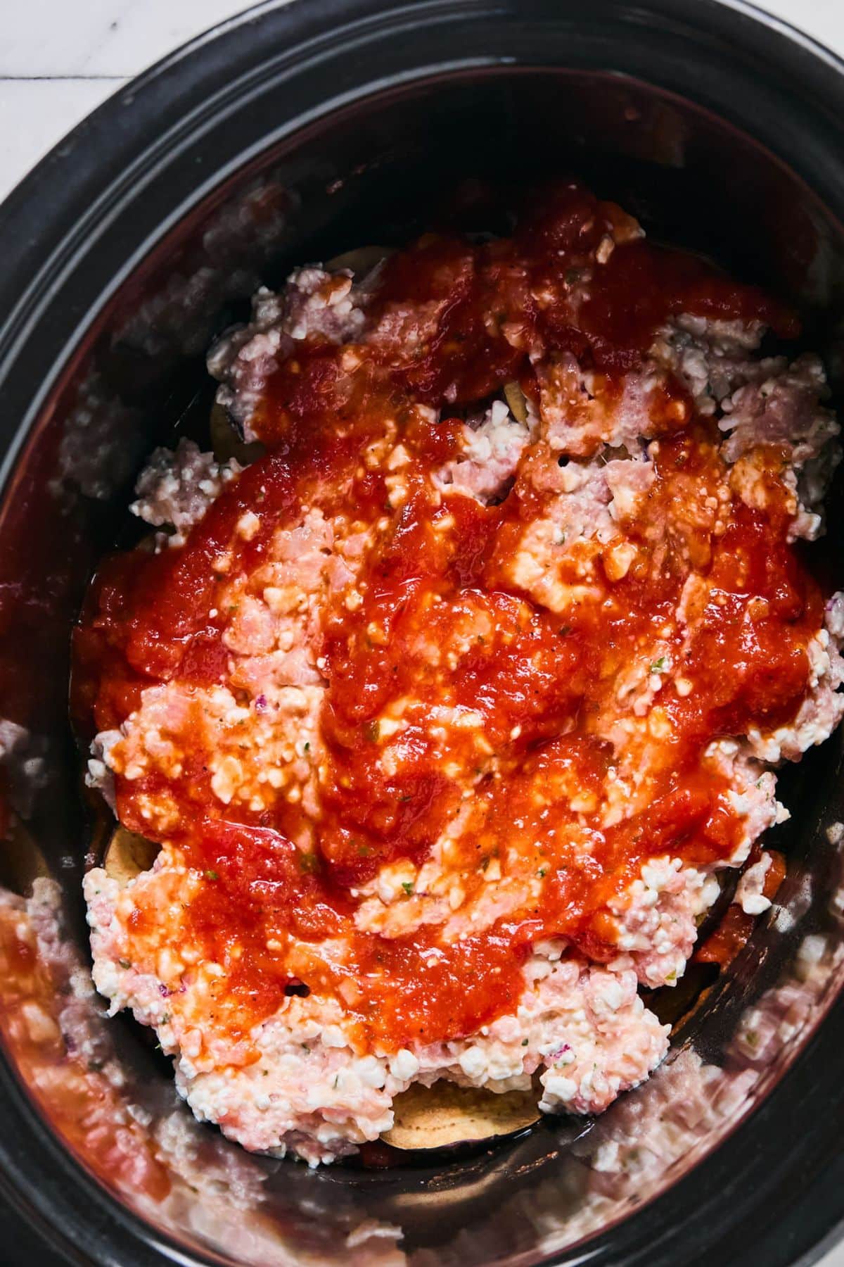 Uncooked lasagna assembled in the crockpot.